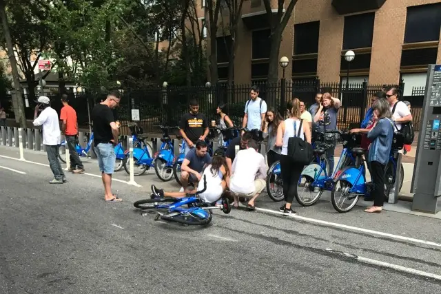 Witnesses tend to the injured cyclist near a Citi Bike stand.